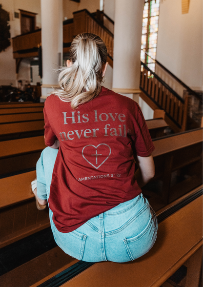 Evertrue T-shirt met tekst “Zijn liefde faalt nooit” – wit biologisch katoenen shirt met geloofsboodschap op de borst en rug.