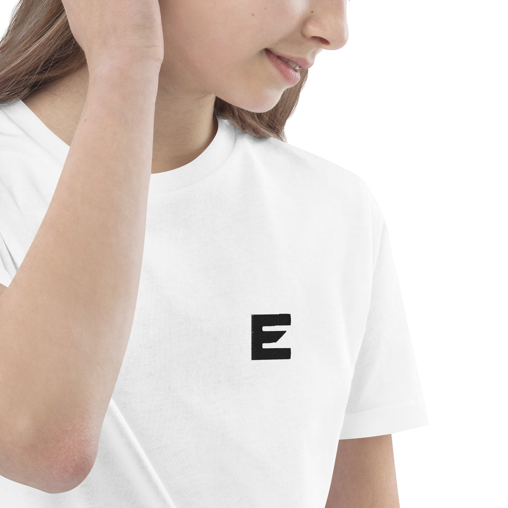 Zwart kruisvormig ontwerp met het woord “TRUST” erin verwerkt, als symbool van vertrouwen in God – Evertrue christelijke kindermode.