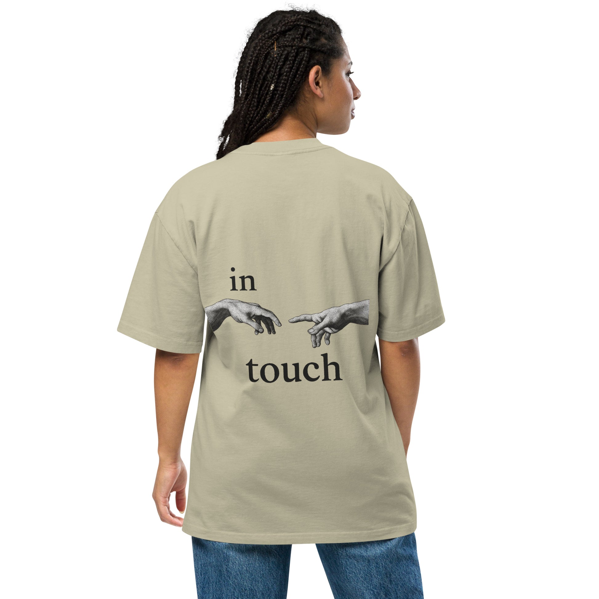 oversized T-shirt met minimalistische print van twee handen die elkaar bijna aanraken, geïnspireerd op Michelangelo’s ‘Schepping van Adam’. Gedragen door een model in urban setting.