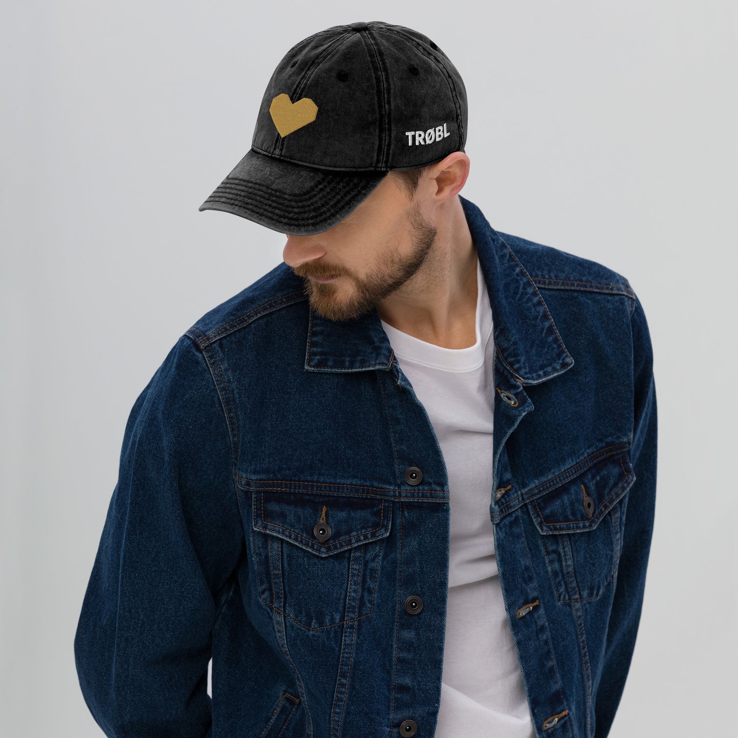 TRØBL cap/pet van vintage gewassen katoen met geborduurd hart aan de voorkant en TRØBL-gouden logo aan de zijkant – unisex streetwear accessoire met ingetogen kracht.