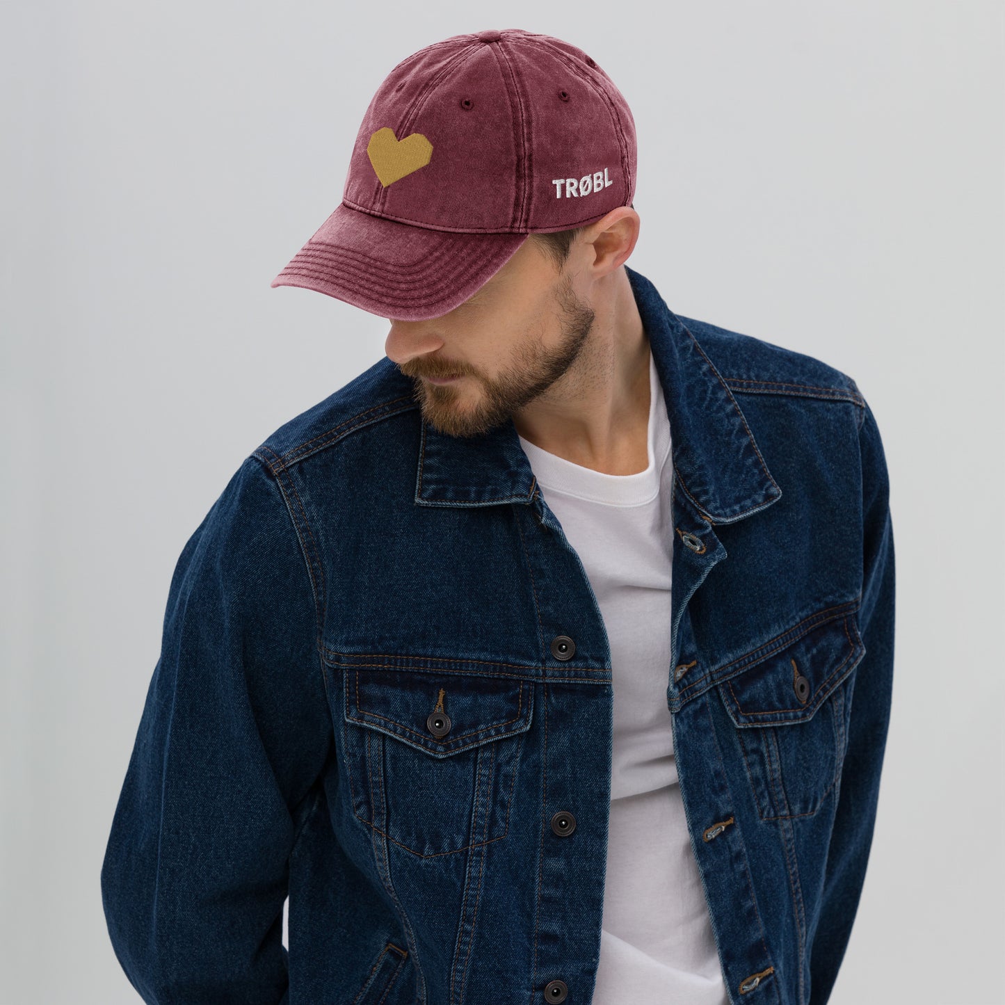 TRØBL cap/pet van vintage gewassen katoen met geborduurd hart aan de voorkant en TRØBL-gouden logo aan de zijkant – unisex streetwear accessoire met ingetogen kracht.
